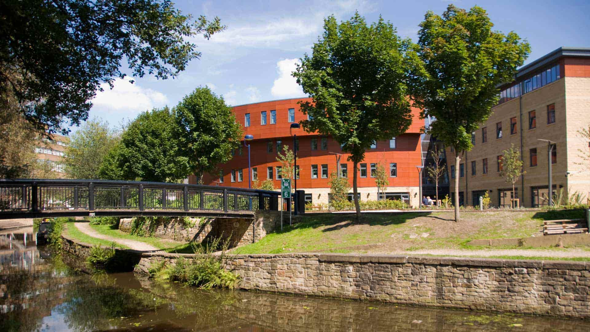 Two students crossing a bridge over the canal to Huddersfield Business School