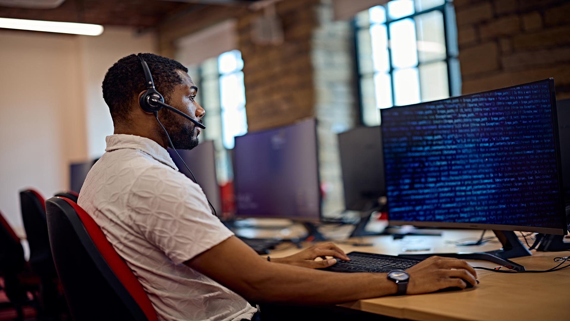 Man sat on a computer wearing a headset