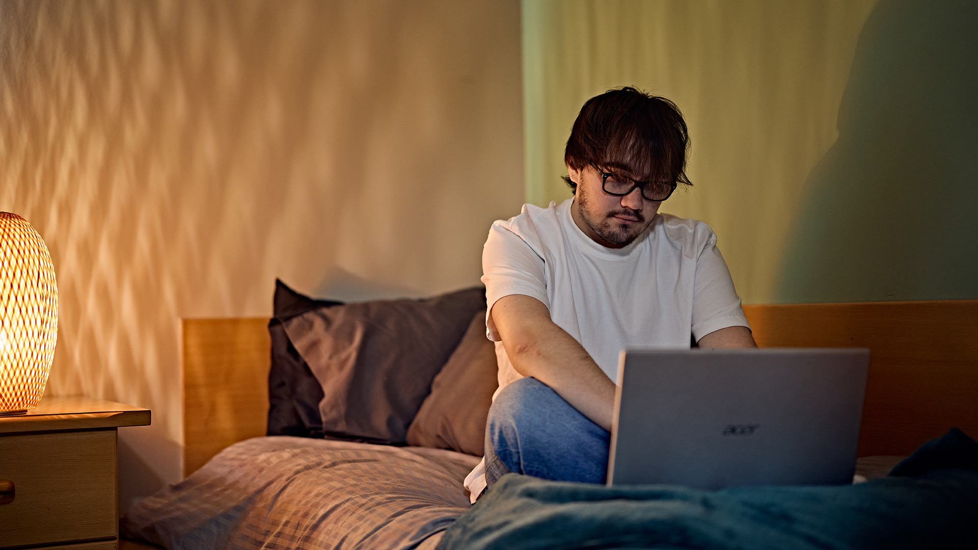 A student studying on a laptop at night on their bed.