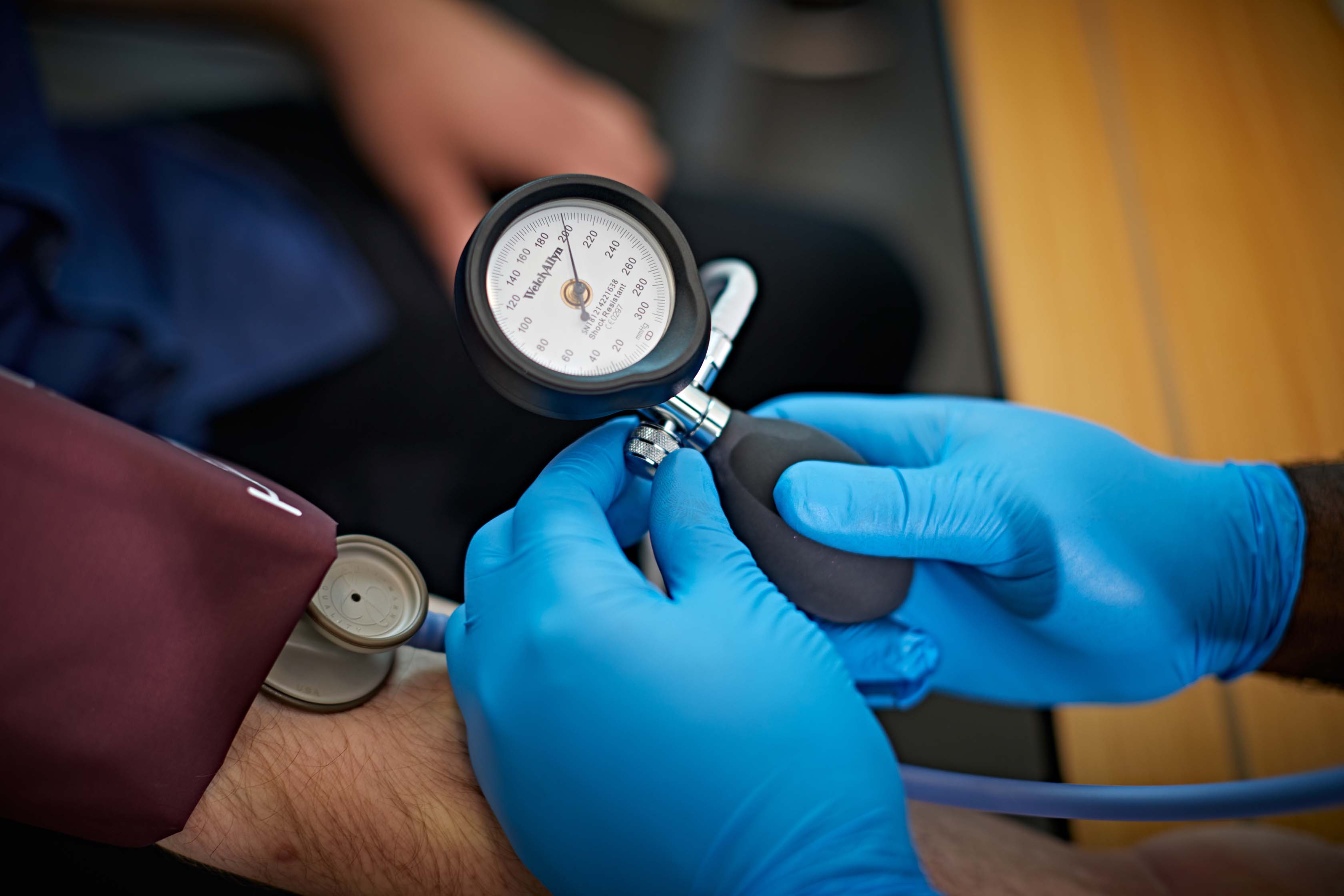 A pair of gloved hands taking someone's blood pressure
