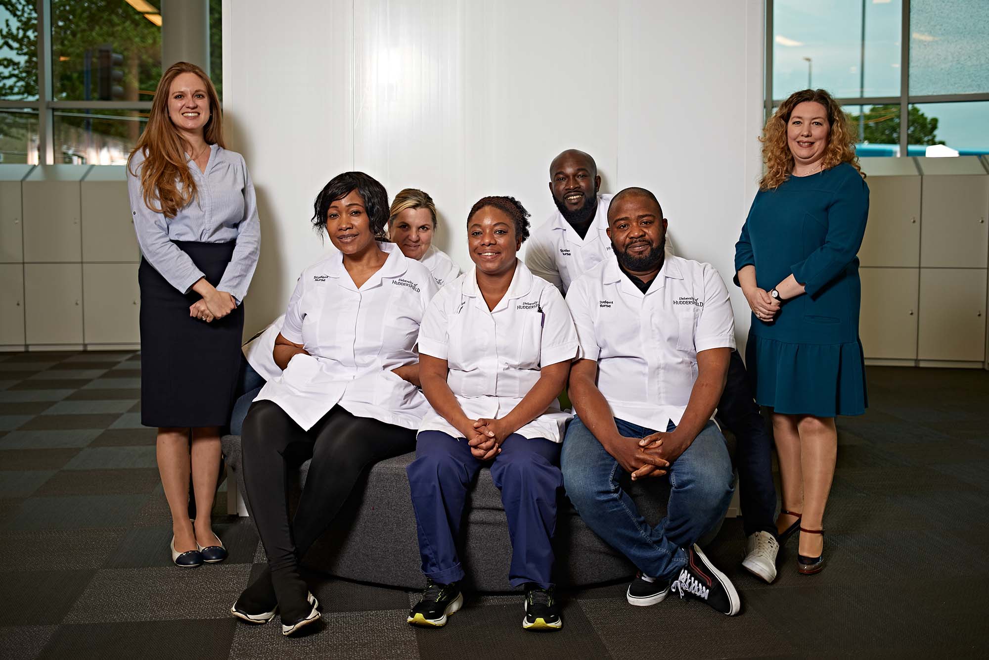 A group of University of Huddersfield nursing students standing with two of their lecturers. They look helpful and friendly.