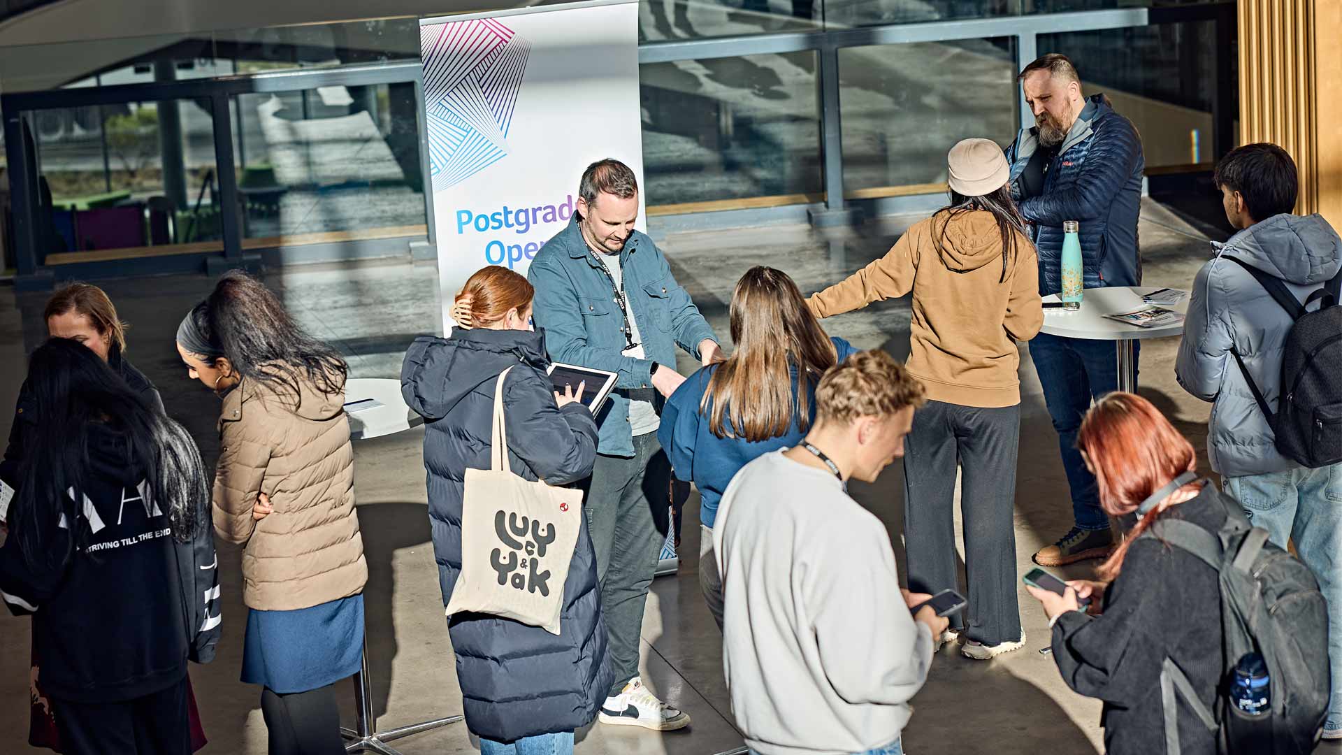 Students chatting with staff at the Postgraduate Open Day fair on campus