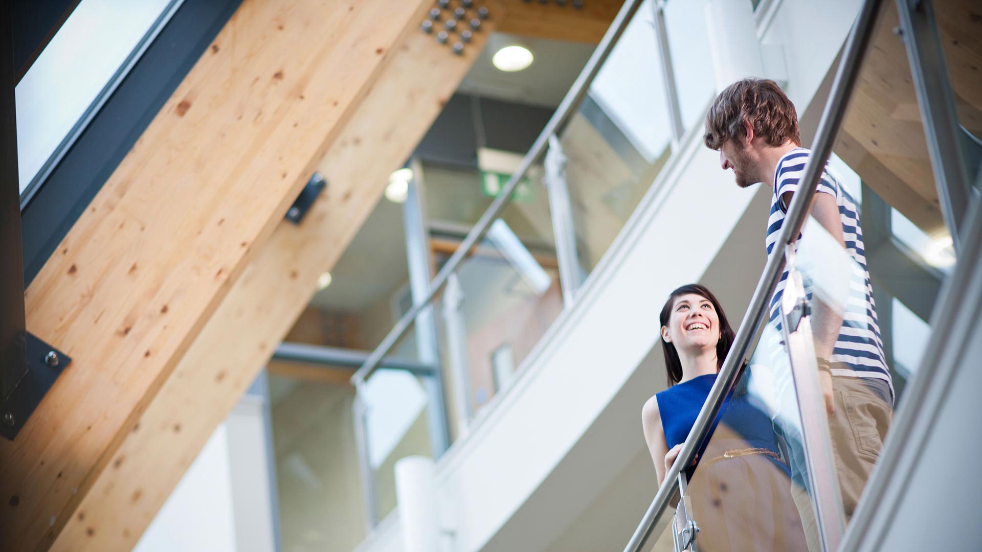 Picture of two students standing next to the glass railing in the business school.